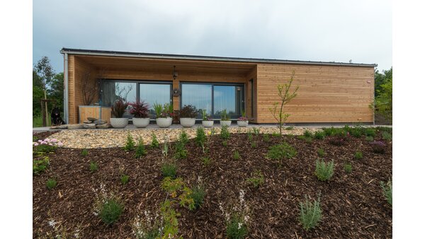 Wooden house with window front pane, flowers on the terrace photographed from the front.