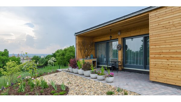 Wooden house with window front pane, flowers on the terrace.