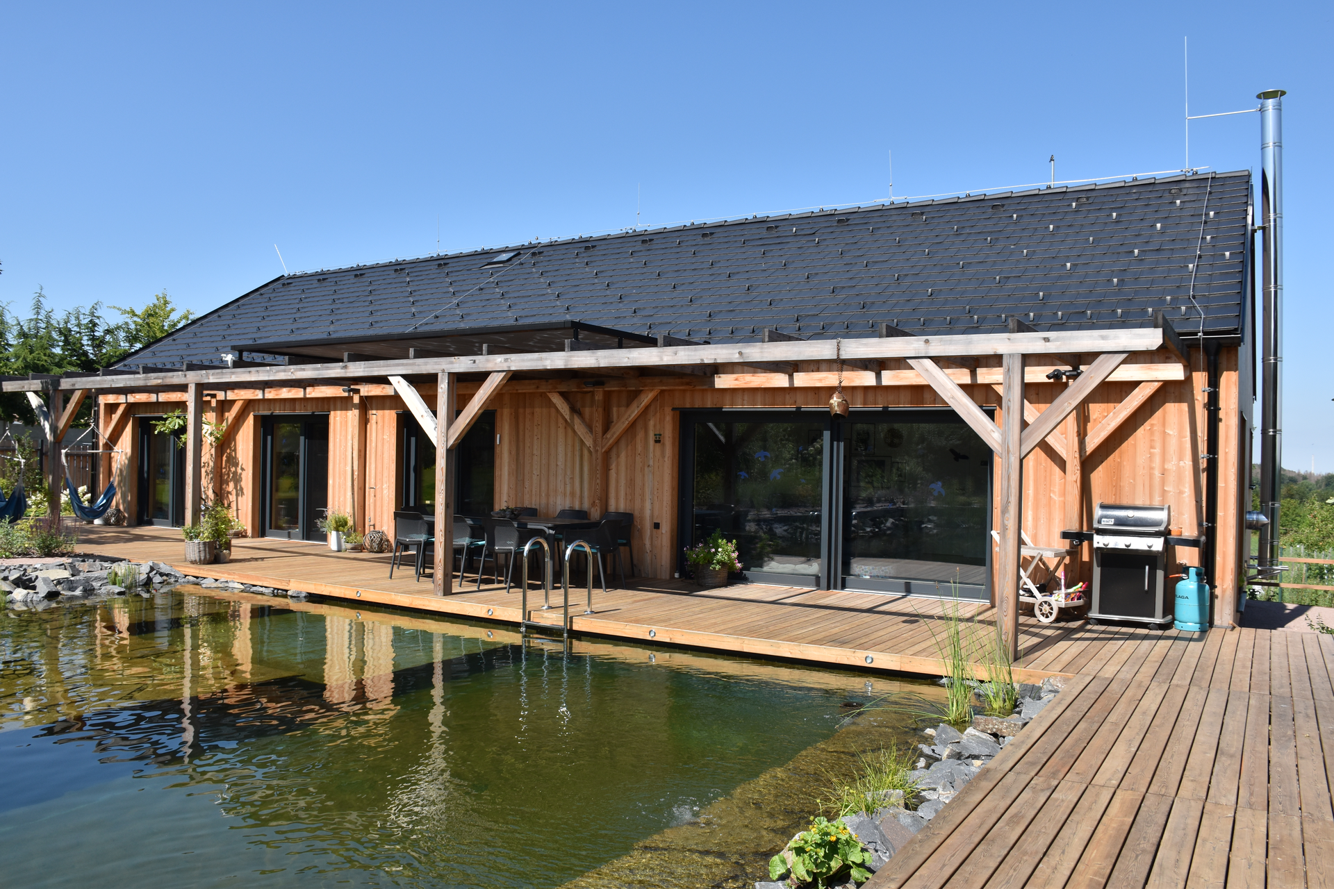 Wooden house with wooden deck and nature pool in front of the house